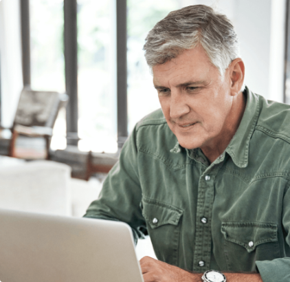 Senior male viewing laptop at home.