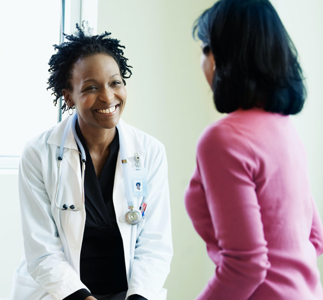 Female doctor talking to a woman in an exam room.