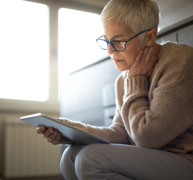 Worried senior woman reading on tablet.