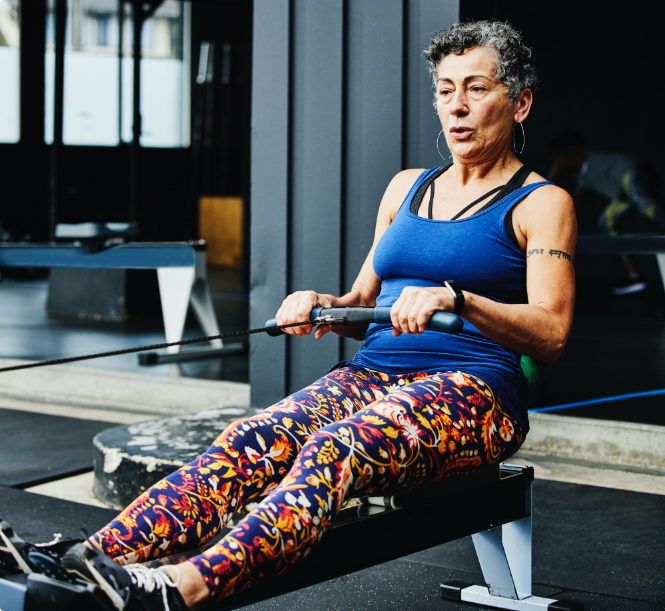 Senior woman working out on rowing machine at an outdoor gym.