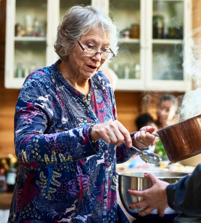 Senior woman wearing glasses and holding saucepan.