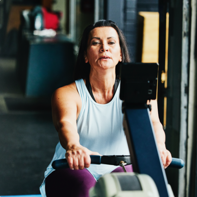 Older woman working out on rowing machine in a gym.