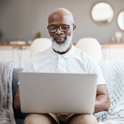 Older male working on his laptop on a couch.